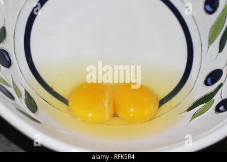 Raw eggs with yolks and whites in a bowl Stock Photo