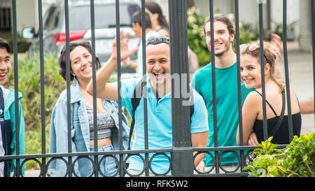 A photo of a group of cheerful and happy international students waving and smiling at the camera. In downtown San Jose, Costa Rica Stock Photo