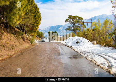 Uphill road in winter at banikhet dalhousie himachal pradesh india with sideways full of snow. Scenic winter view from the asphalt road covered with s Stock Photo
