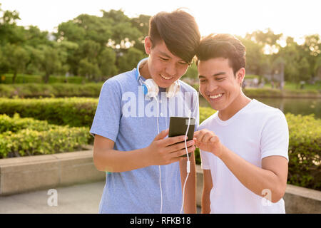 Young Asian man and young Asian teenage boy at the park together Stock Photo