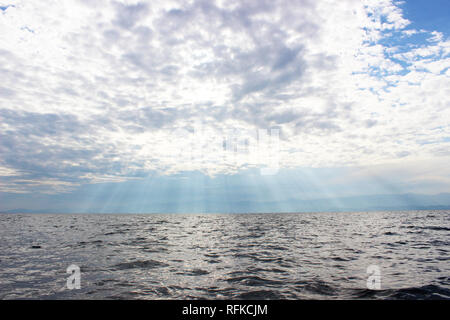 Rays of sunlight shining through the clouds on Lake Kivu, Rwanda. Beautiful heavenly and tranquil scene. Stock Photo