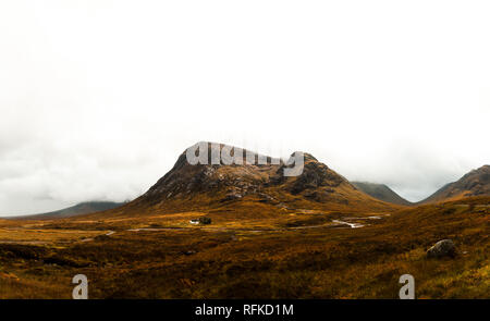 Panorama of white litte Scottish cottage near Glen Coe on the way to the Isle of Skye with fog covered mountain range (Glen Coe, Scotland, Europe) Stock Photo