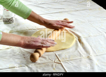 Making of a strudel, preparing dough with rolling pin on a kitchen table Stock Photo