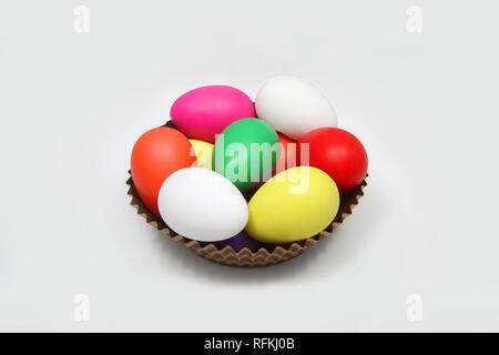 Multi colored easter eggs in a brown basket against a white background. Stock Photo
