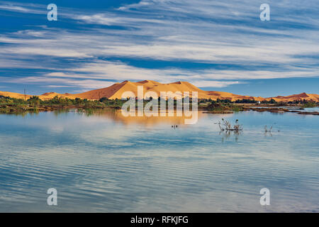 A sand hill (dune) of Erg Chebbi and reflection on lake. Landscape shot taken near town Merzouga, Sahara Desert, Morocco in November. Stock Photo