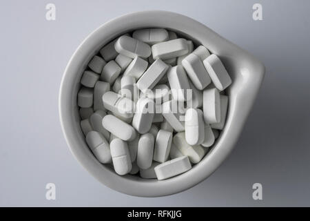 Several pills inside white mortar, conceptual image Stock Photo