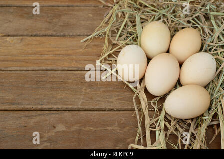 Egg in hay nest on old wooden table background Stock Photo