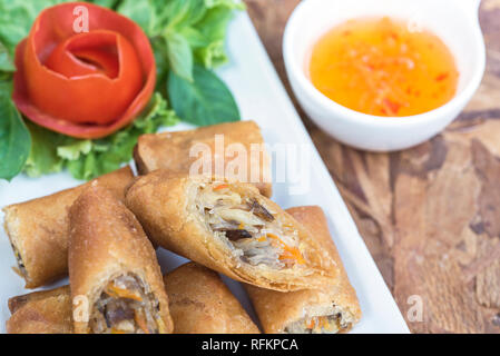 Egg roll or Spring roll or Popiah Vietnamese cuisine in Thai style with sweet suace on wooden table Stock Photo
