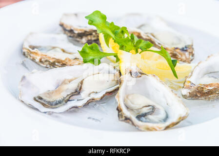 Selective focus point on fresh oysters shell with lemon Stock Photo