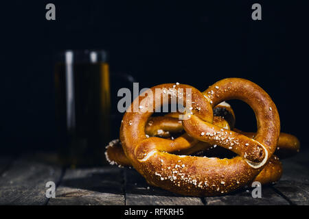 Close-up pretzel on the bar counter on background of glass of beer. Stock Photo