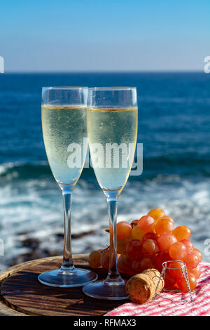 Champagne, prosecco or cava served with pink grape in two glasses on outside terrace with sea view close up Stock Photo