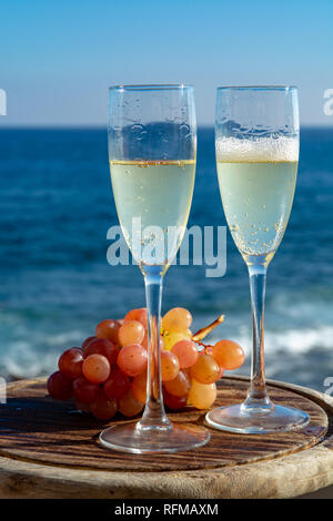 Champagne, prosecco or cava served with pink grape in two glasses on outside terrace with sea view close up Stock Photo