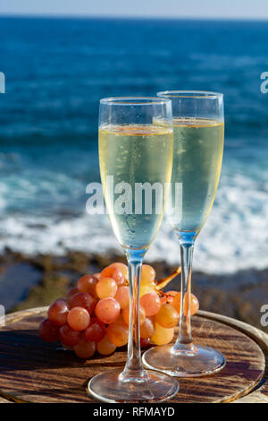 Champagne, prosecco or cava served with pink grape in two glasses on outside terrace with sea view close up Stock Photo