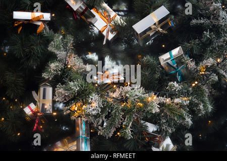 Christmas presents with ribbons in boxes hanging on festive Christmas tree Stock Photo