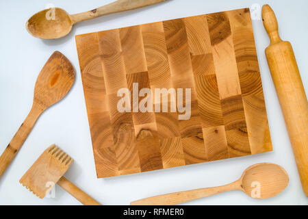 Handmade wooden board and kitchen tools on white background: wooden spoon, wooden hammer; rolling pin. Image with copy space, Stock Photo