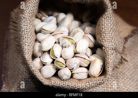 Pistachios nuts in linen bag on wooden table. Food mix background, top view, copy space, banner Stock Photo