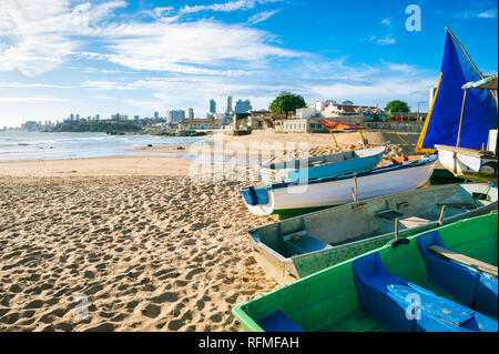 Traditional wooden boats painted in bright blues and greens line up on the shore of the fishing village of Rio Vermelho, in Salvador, Bahia, Brazil Stock Photo