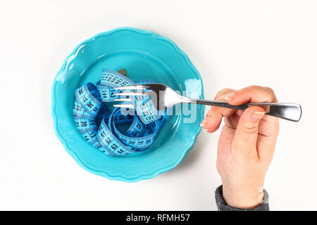 Empty plate with blue measure tape, fork on the wooden white background. Diet food concept. Top view. Weight loss concept. Stock Photo