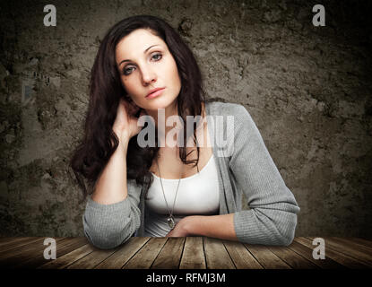 Beautiful young woman leaning on wooden table Stock Photo
