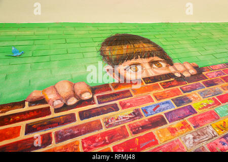 Street art in Palemo Soho district of Buenos Aires, Argentina, featuring a young male looking over a brick wall. Stock Photo