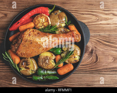 Roasted turkey leg with vegetables, carrots, peppers, potatoes vegetables in frying pan Stock Photo