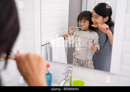 mother and daughter brushing teeth in the bathroom sink Stock Photo