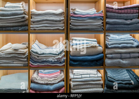 Modern wooden wardrobe with different types of clothing folded and stacked on top of each other in cabinets Stock Photo