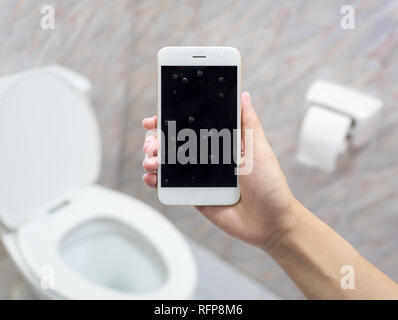 Human hand holding wet smart phone in water closet. Water damage, waterproof concept. Stock Photo