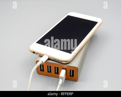 Smart phone charging with multiport USB power adaptor on gray background, Selective focus Stock Photo
