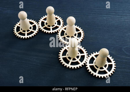 Teamwork success concept. Gear wheels and wooden figures. Stock Photo