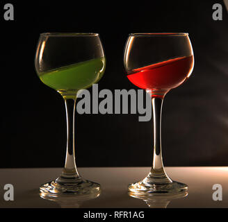 Wine glasses with different coloured liquids tilted at an angle Stock Photo