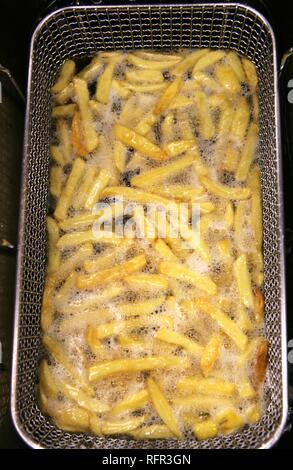 Chips frying in a deep fryer Stock Photo