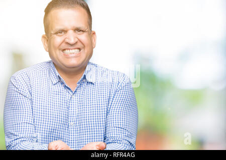 Middle age arab business man over isolated background Smiling with hands palms together receiving or giving gesture. Hold and protection Stock Photo