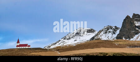 Vik Church on skyline, Iceland, at dusk in Winter with snow covered mountain peaks in background Stock Photo