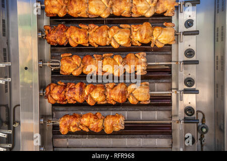 Chickens being spit roasted on the side of a van in spanish market Stock Photo