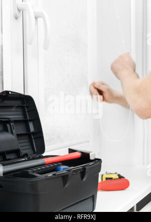 Man testing cassette roller blinds on windows. Stock Photo