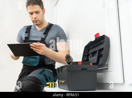 Professional contractor sitting at window with tablet pc. Stock Photo