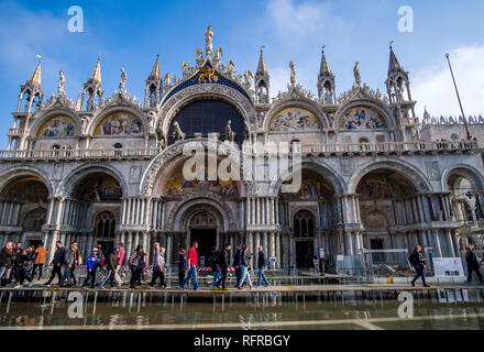 Many tourists are walking on footbridges in front of Saint Mark's Basilica, Basilica di San Marco, San Marco Square, Piazza San Marco flooded during t Stock Photo