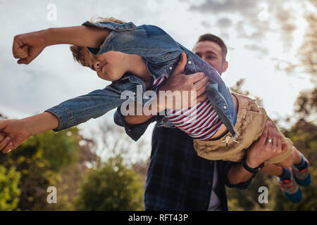 Cute young boy flying in hands of his dad. Small kid playing with his father at the park. Stock Photo