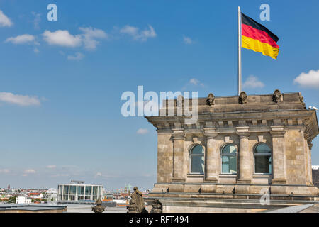 Closeup view of famous Reichstag building tower and German flag with Berlin cityscape. Mitte district, Germany. Stock Photo