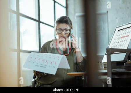 Dark-haired pregnant businesswoman having no free time during month Stock Photo