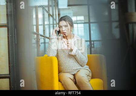 Pregnant woman holding her blue smartphone while calling husband Stock Photo