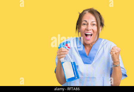 Middle age brunette cleaner woman wearing housework uniform over isolated background screaming proud and celebrating victory and success very excited, Stock Photo