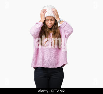 Young beautiful brunette woman wearing sweater and winter hat over isolated background suffering from headache desperate and stressed because pain and Stock Photo