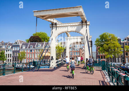 Cyclists riding across the Magere brug (Skinny Bridge) spanning the River Amstel, Amsterdam, North Holland, Netherlands, Europe Stock Photo