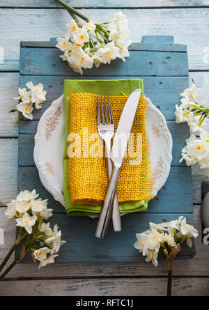 Spring table setting. Narcissus flower. Fork and knife on Easter table. Holiday table setting. Top flatlay ovehead view Stock Photo