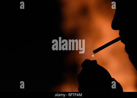 A man is seen smoking near a bonfire during 'Las Luminarias' tradition in the small village of Rebollo de Duero, north of Spain. The tradition, which is hundreds of years old, is meant to purify and protect, with a big bonfire,  the animals and people in the coming year. Hundreds of villages and towns of Spain celebrated this tradition during centuries, but nowdays the celebration has been lost in many of them. Stock Photo