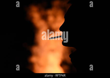 A man is seen smoking near a bonfire during 'Las Luminarias' tradition in the small village of Rebollo de Duero, north of Spain. The tradition, which is hundreds of years old, is meant to purify and protect, with a big bonfire,  the animals and people in the coming year. Hundreds of villages and towns of Spain celebrated this tradition during centuries, but nowdays the celebration has been lost in many of them. Stock Photo