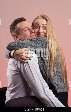 Funny couple making big hug isolated on pink background Stock Photo