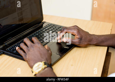 Closeup of two hands typing on the keyboard of a laptop on a table. Stock Photo